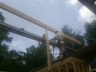 Carpenter setting a ridge beam over a new addition frame — Ice Dam Removal by Roofing Brothers in Hewlett