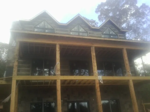 Dormers and porch framing on a large log home under construction — Roof Coating work by our crew in Hewlett