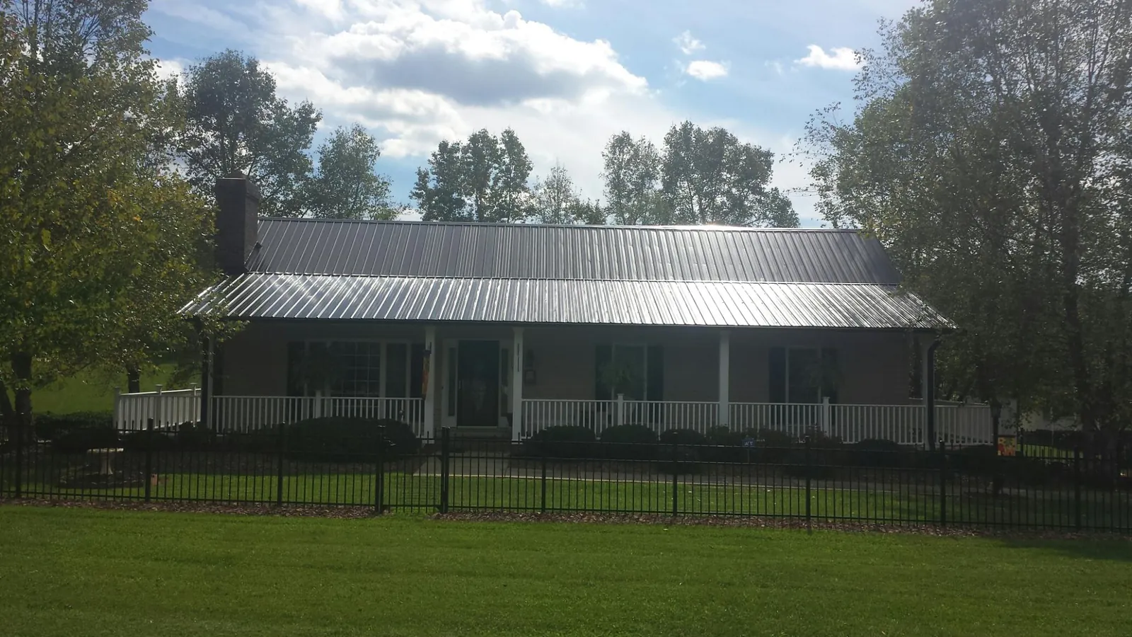 Gray metal roof on a brick ranch with a full width front porch — Gutter Guard Installation work by our crew in Hewlett
