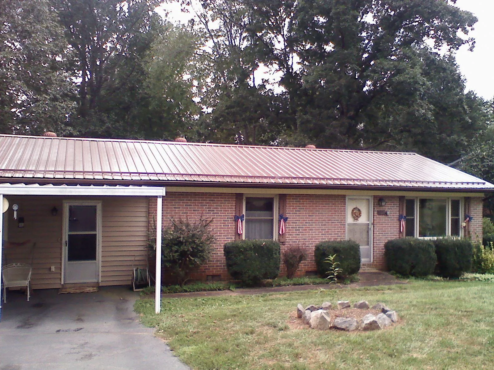 Bronze metal roof and carport on a brick ranch home — Roof Repair work by our crew in Hewlett